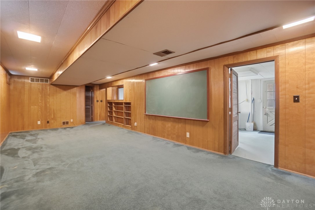 6119 Flemington Road Dayton, OH 45459 - Photo 42 of 76 This versatile room features warm wood paneling, built-in shelving, and soft carpeting.