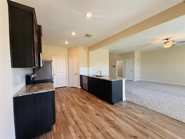 a large kitchen with kitchen island granite countertop a sink and a stove top oven with wooden floor