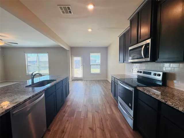 a kitchen with stainless steel appliances granite countertop a stove a sink and a microwave