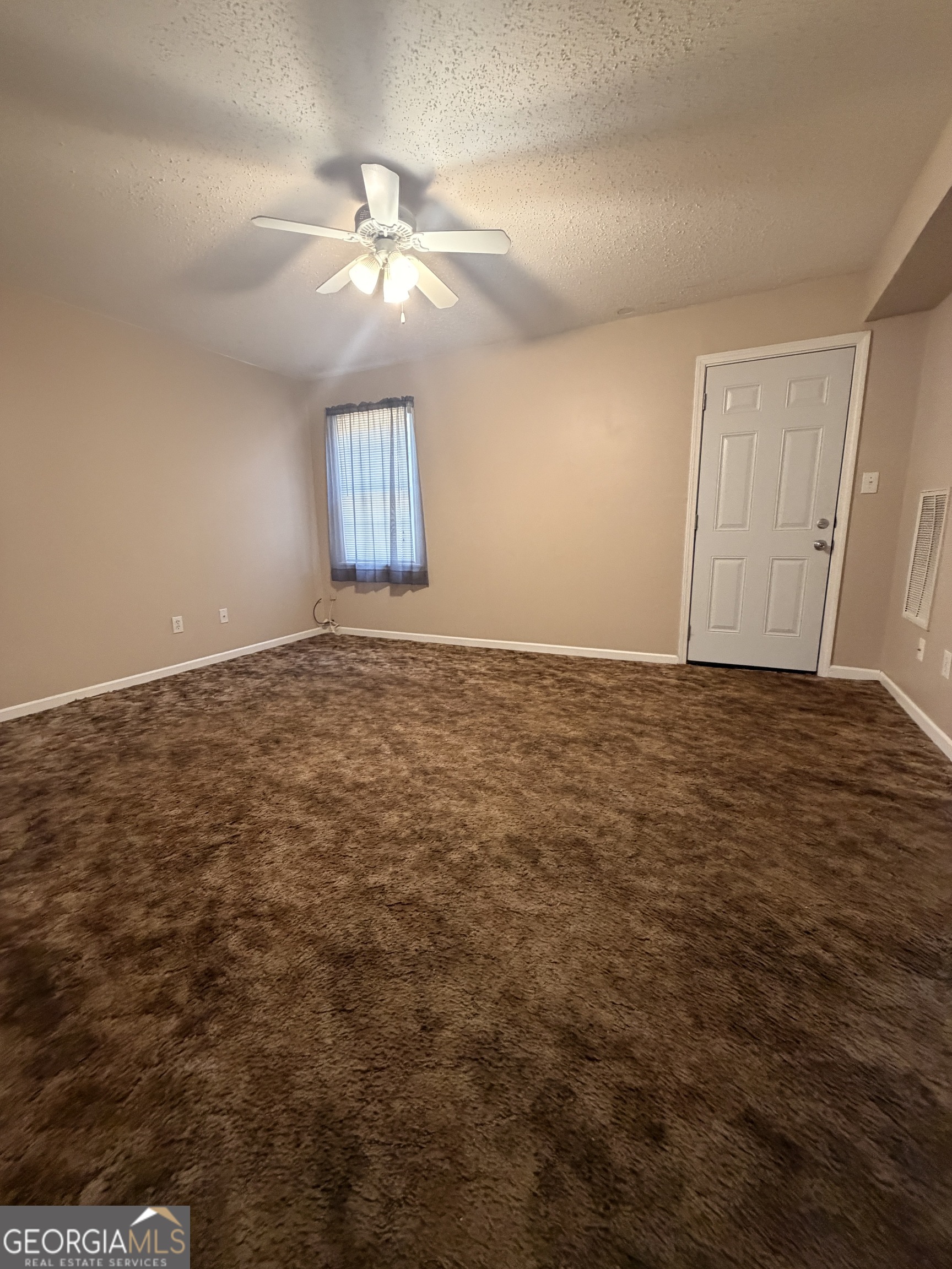 an empty room with closet and a ceiling fan