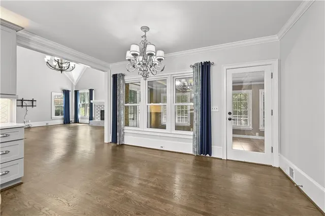 a view of a room with wooden floor chandelier and windows