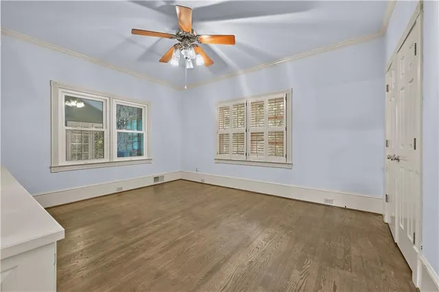 an empty room with windows and chandelier fan