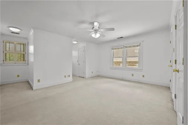 an empty room with windows and ceiling fan