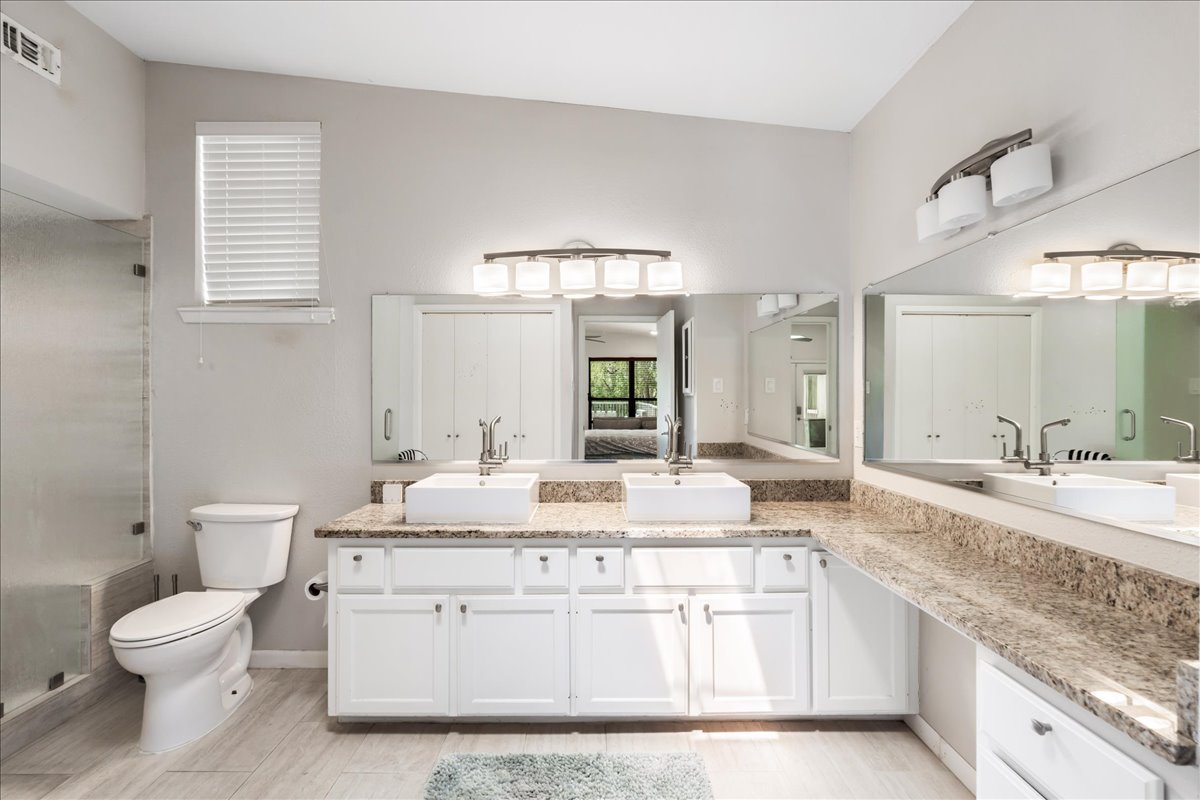 207 Rogers Ridge Street San Marcos, TX 78666 - Photo 14 of 35 The beautifully appointed primary bath combines elevated tilework, contemporary fixtures, a refined vanity, and expansive glass shower doors, creating a light-filled space with an understated sense of luxury.