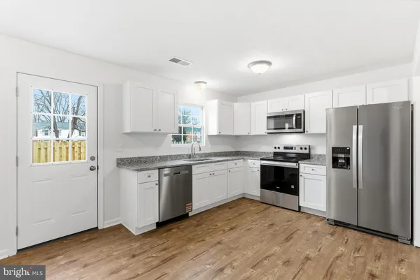 a kitchen with granite countertop a refrigerator stove top oven and sink