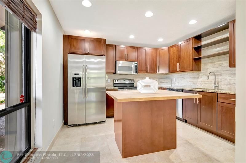 9268 Sable Ridge Circle, Unit C Boca Raton, FL 33428 - Photo 5 of 50 a kitchen with stainless steel appliances granite countertop a refrigerator a sink a stove and a refrigerator with wooden floor