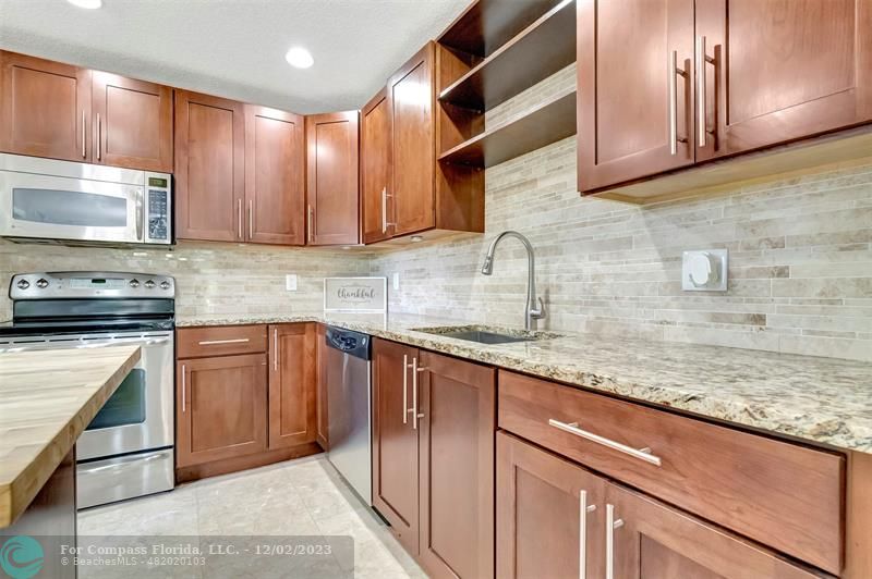 9268 Sable Ridge Circle, Unit C Boca Raton, FL 33428 - Photo 7 of 50 a kitchen with stainless steel appliances granite countertop wooden cabinets a stove a sink and dishwasher