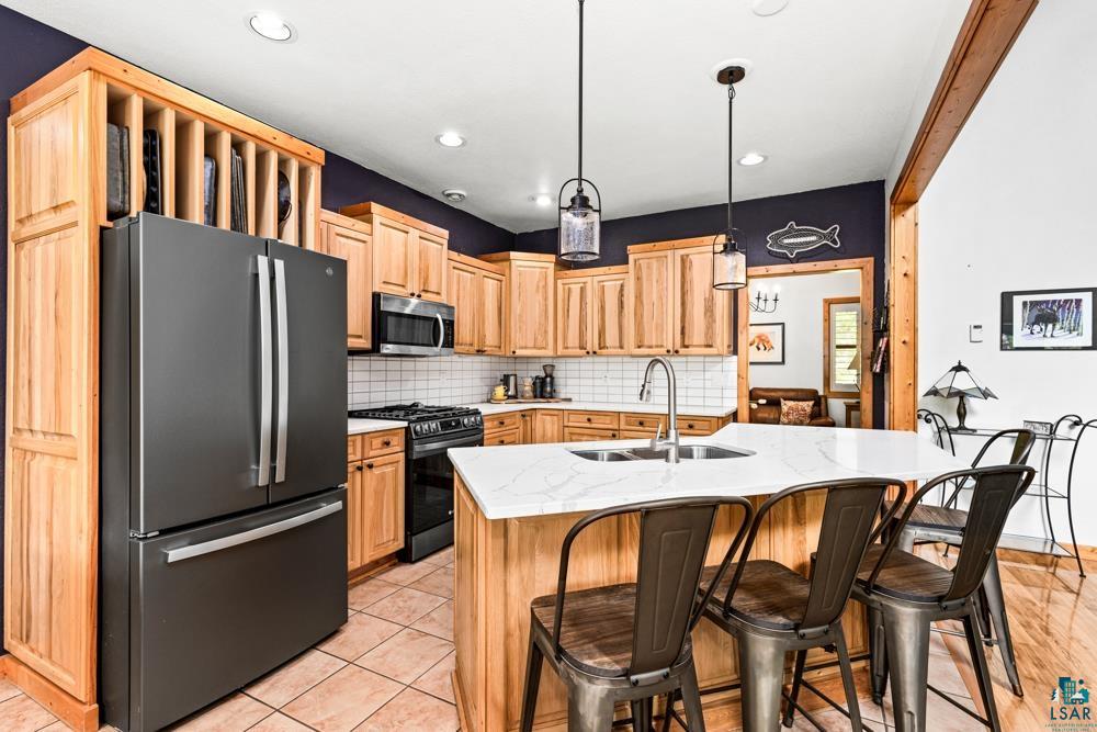 4471 South Rockmont Road South Range, WI 54874 - Photo 12 of 48 Kitchen with gas range, hanging light fixtures, tasteful backsplash, fridge, and sink