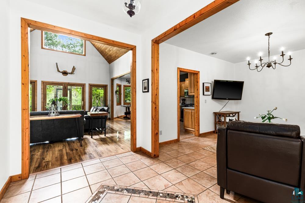 4471 South Rockmont Road South Range, WI 54874 - Photo 18 of 48 Living room featuring a notable chandelier, light tile flooring, and vaulted ceiling