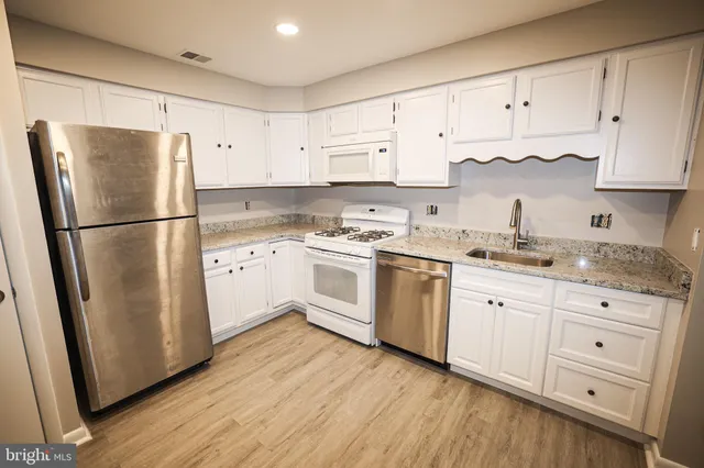 a kitchen with white cabinets white stainless steel appliances and sink