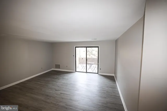 a view of an empty room with wooden floor and window