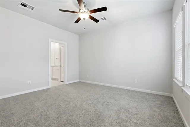an empty room with windows and fan