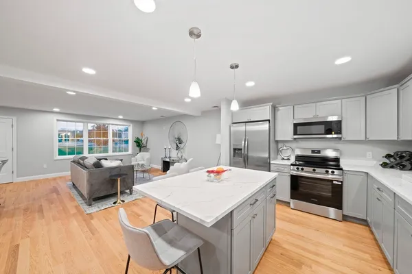a large kitchen with kitchen island a stove a sink a refrigerator and a dining table with wooden floor
