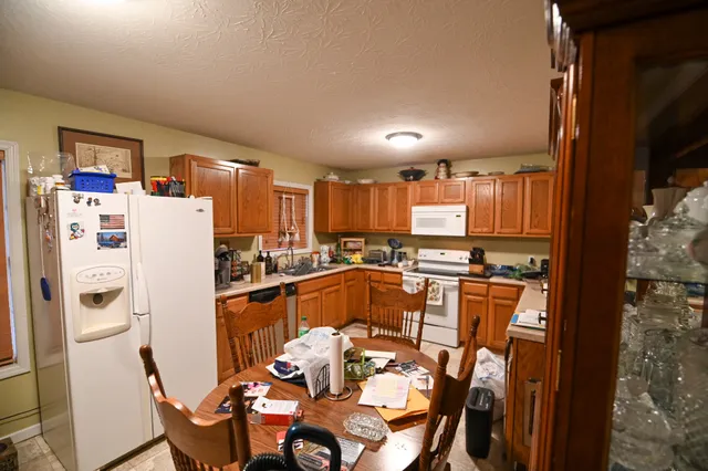 a kitchen with stainless steel appliances a refrigerator a sink a dining table and chairs