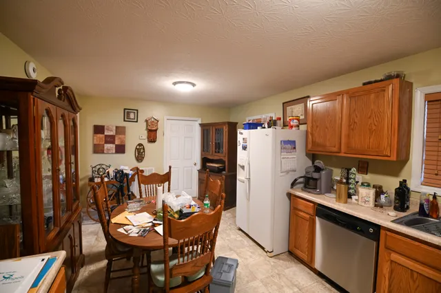 a kitchen with stainless steel appliances sink refrigerator dining table and chairs