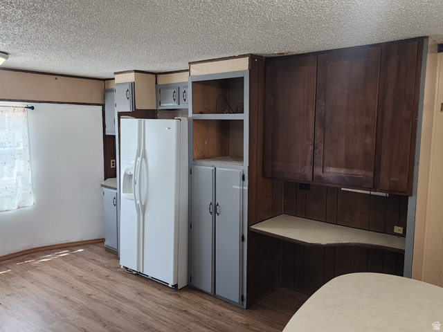 332 Joshua Street Tooele, UT 84074 - Photo 11 of 16 Kitchen area featuring wood-finish flooring, a white side-by-side refrigerator, gray lower cabinetry, and dark wood-tone upper cabinetry