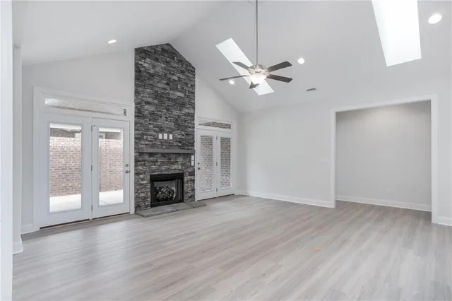 an empty room with wooden floor fireplace fan and windows
