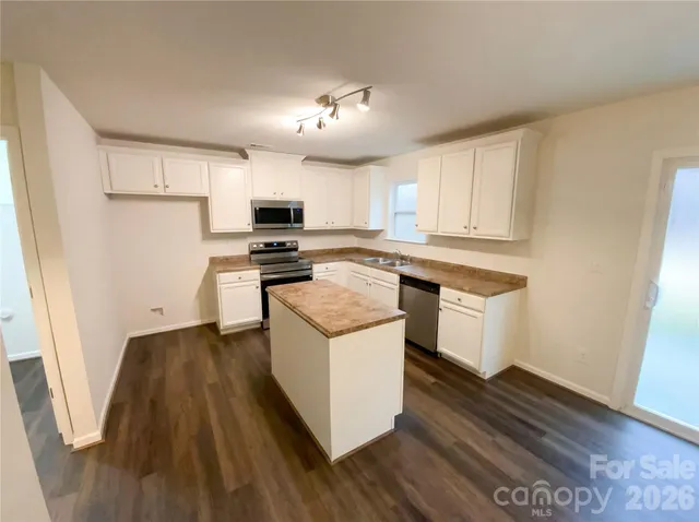 a kitchen with granite countertop a stove top oven a sink dishwasher and a refrigerator with wooden floor