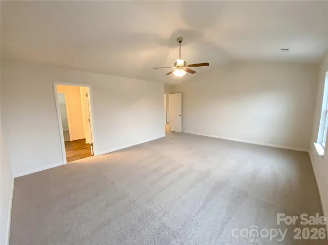 an empty room with a chandelier fan and windows