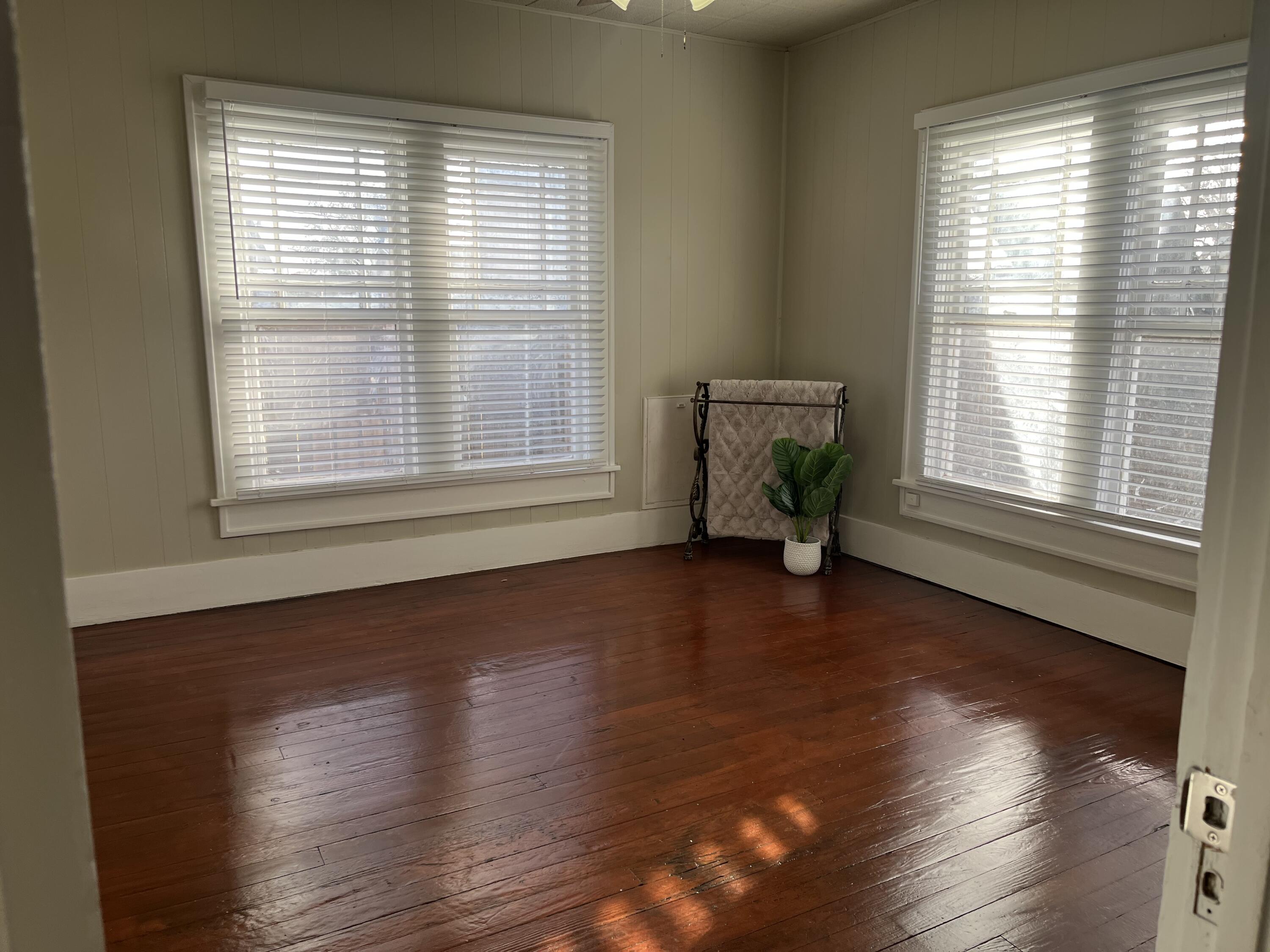 605 South 10th Street Slaton, TX 79364 - Photo 11 of 19 a view of an empty room with wooden floor and a window