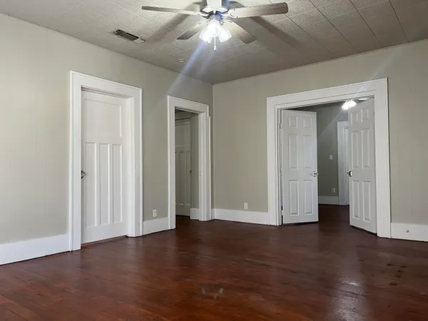 an empty room with wooden floor and ceiling fan