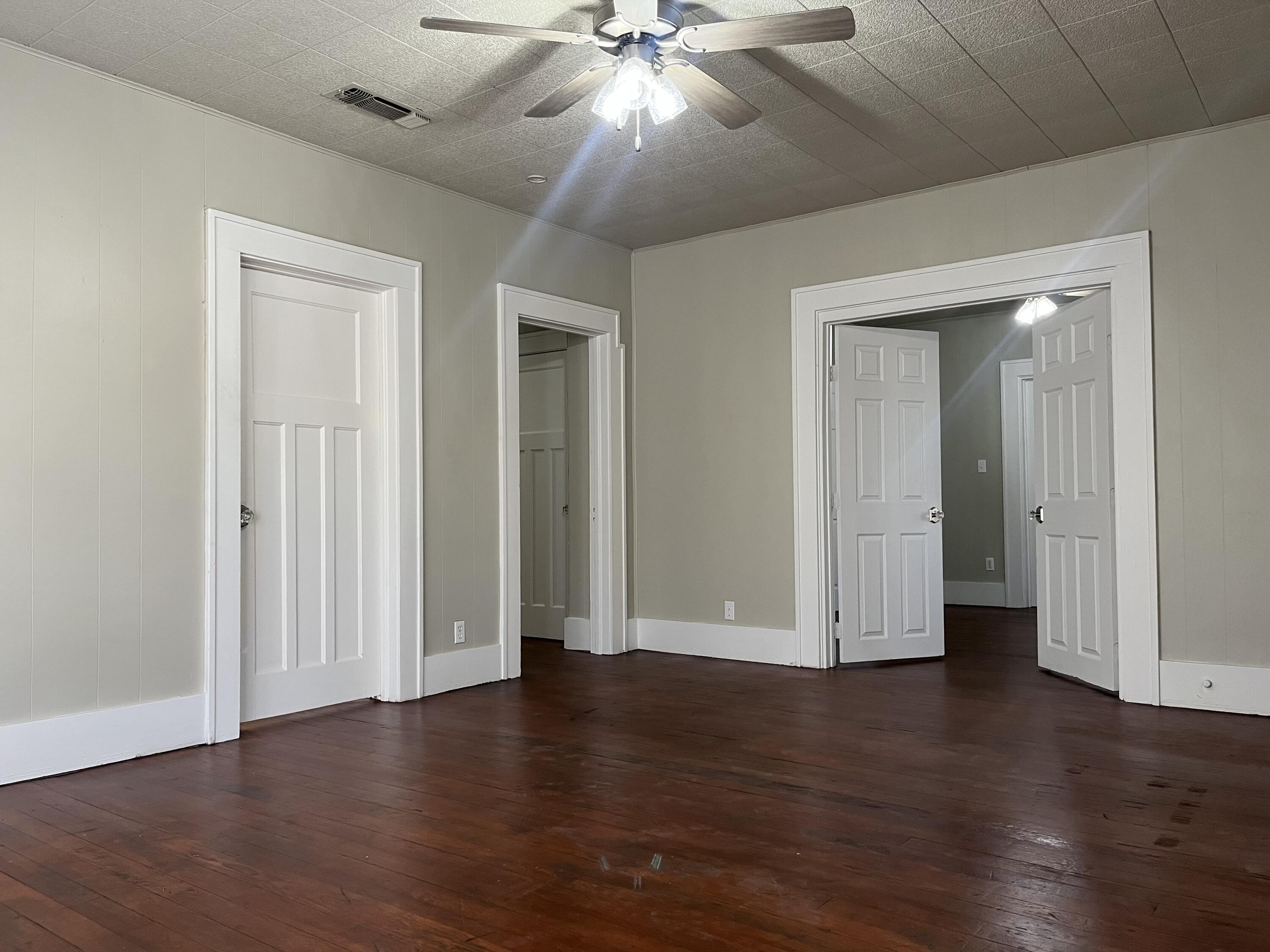 605 South 10th Street Slaton, TX 79364 - Photo 3 of 19 an empty room with wooden floor and ceiling fan