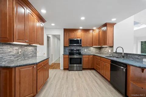 a kitchen with stainless steel appliances granite countertop wooden cabinets a stove top oven a sink and dishwasher