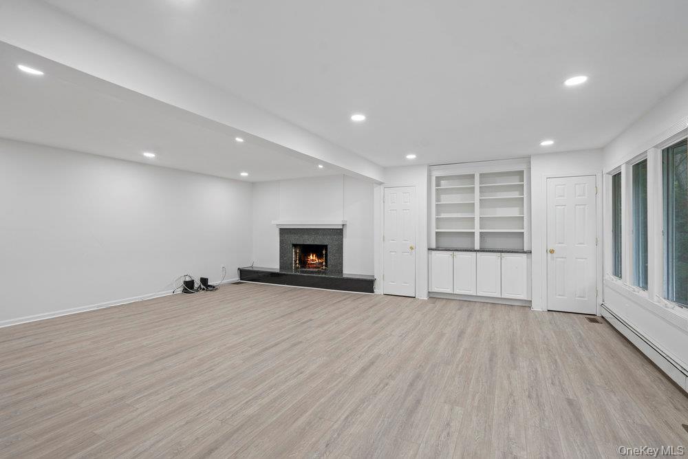 83 Shore Road Mount Sinai, NY 11766 - Photo 10 of 33 an empty room with wooden floor and fireplace