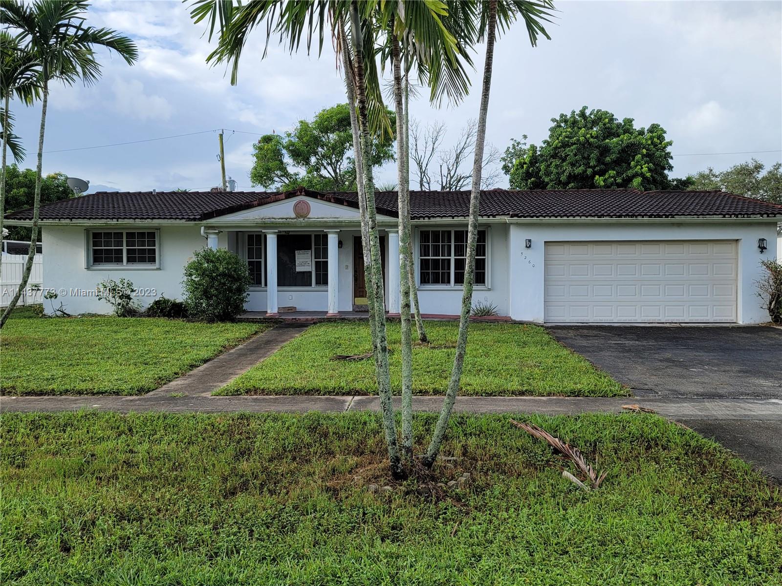 a view of a house with a yard and palm trees