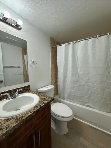 a bathroom with a granite countertop sink toilet and shower