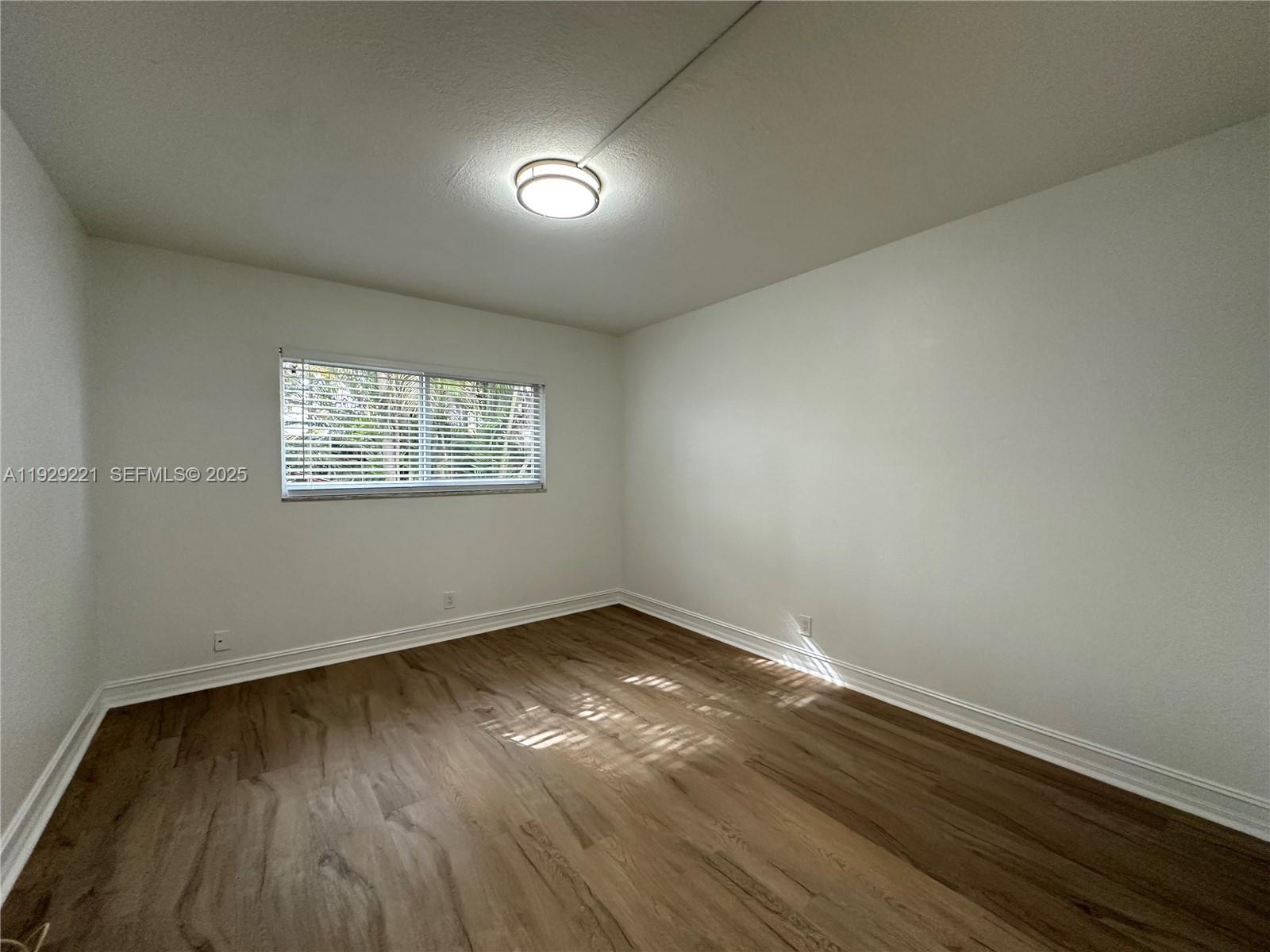1400 Northeast 56th Street, Unit 105 Fort Lauderdale, FL 33334 - Photo 19 of 42 an empty room with wooden floor and windows