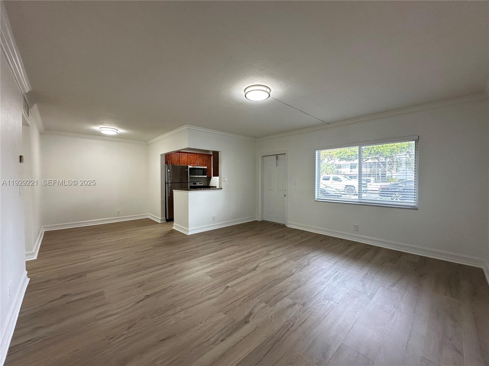 1400 Northeast 56th Street, Unit 105 Fort Lauderdale, FL 33334 - Photo 2 of 42 wooden floor in an empty room with a window