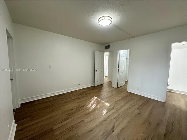 a view of an empty room with wooden floor