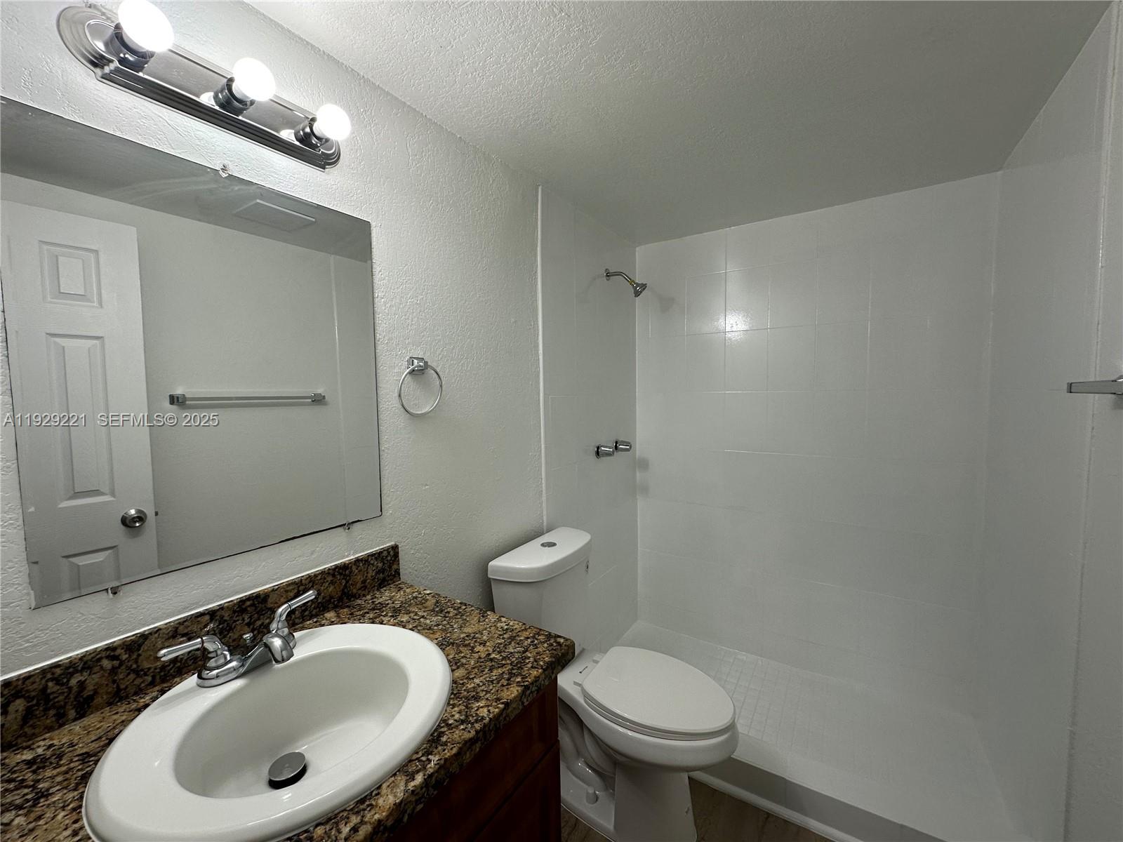 1400 Northeast 56th Street, Unit 105 Fort Lauderdale, FL 33334 - Photo 25 of 42 a bathroom with a sink toilet a mirror and vanity