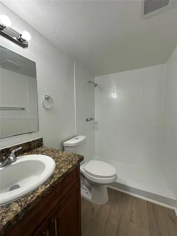 a bathroom with a granite countertop sink toilet and a mirror