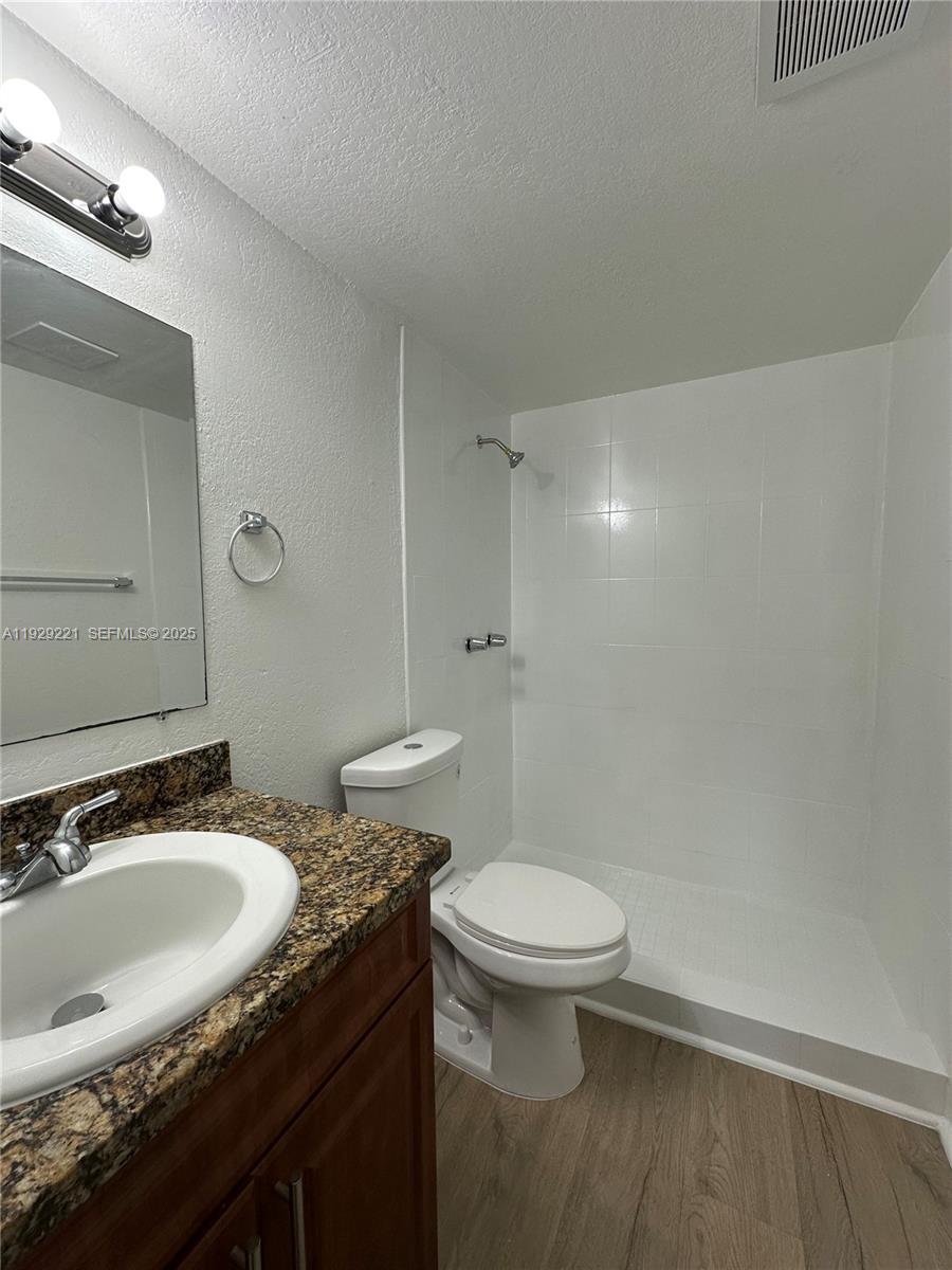 1400 Northeast 56th Street, Unit 105 Fort Lauderdale, FL 33334 - Photo 26 of 42 a bathroom with a granite countertop sink toilet and a mirror