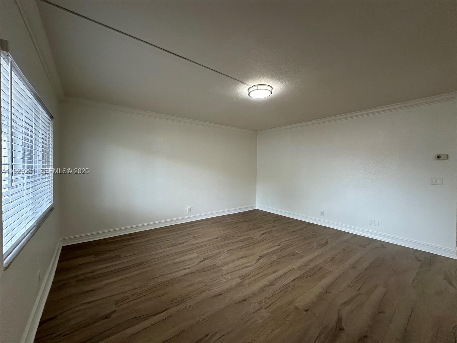 1400 Northeast 56th Street, Unit 105 Fort Lauderdale, FL 33334 - Photo 7 of 42 an empty room with wooden floor and windows