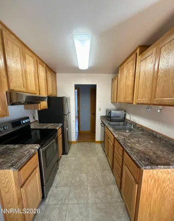 a large kitchen with granite countertop a stove top oven a sink dishwasher a dining table and chairs with wooden floor