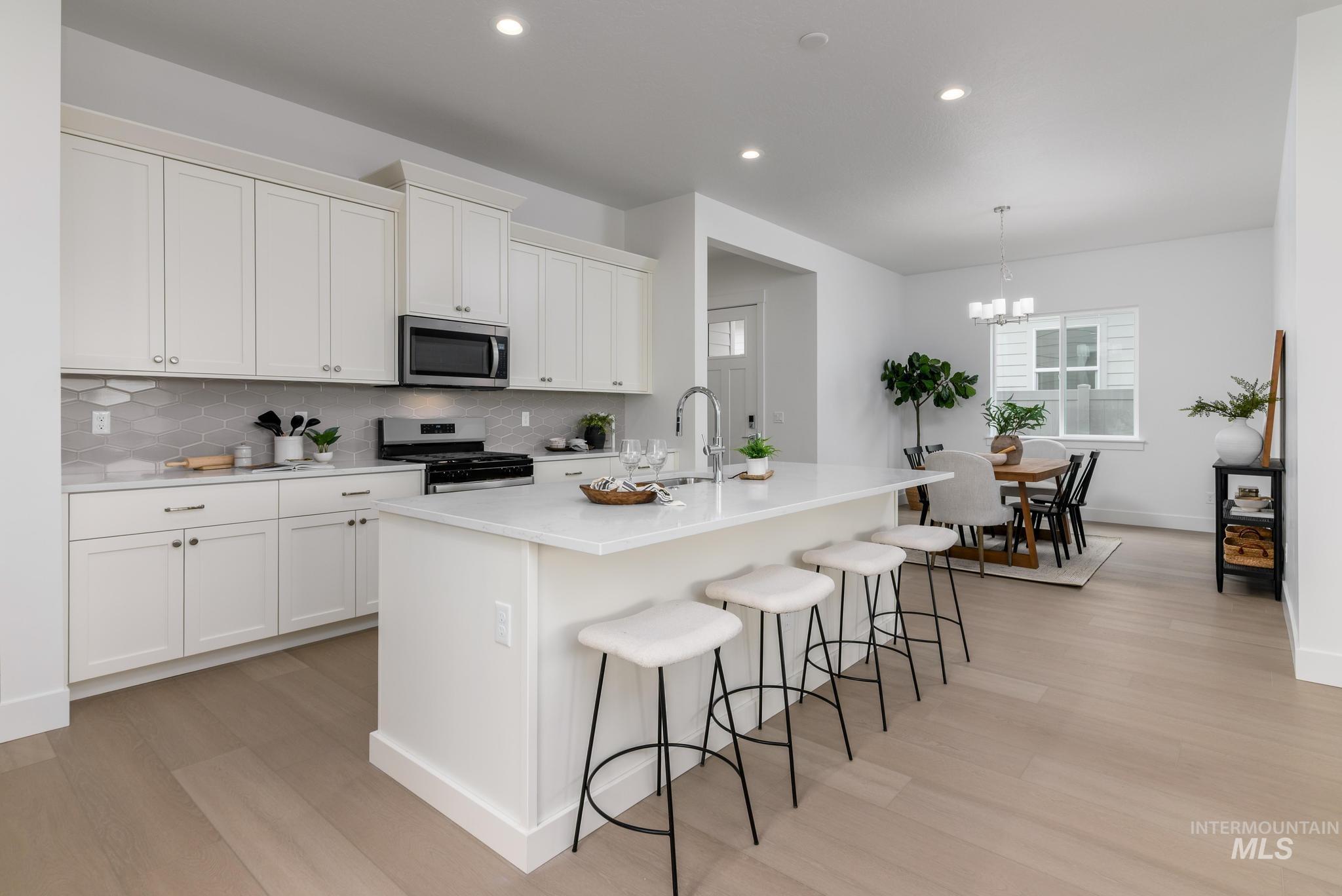 8555 West Fanning Street Star, ID 83669 - Photo 5 of 11 Kitchen featuring stainless steel appliances, a kitchen breakfast bar, a kitchen island with sink, light wood-style floors, and white cabinets