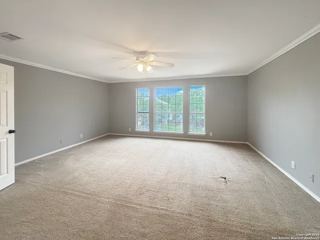 an empty room with windows and chandelier fan