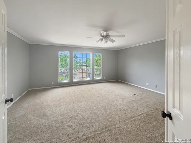an empty room with windows and fan