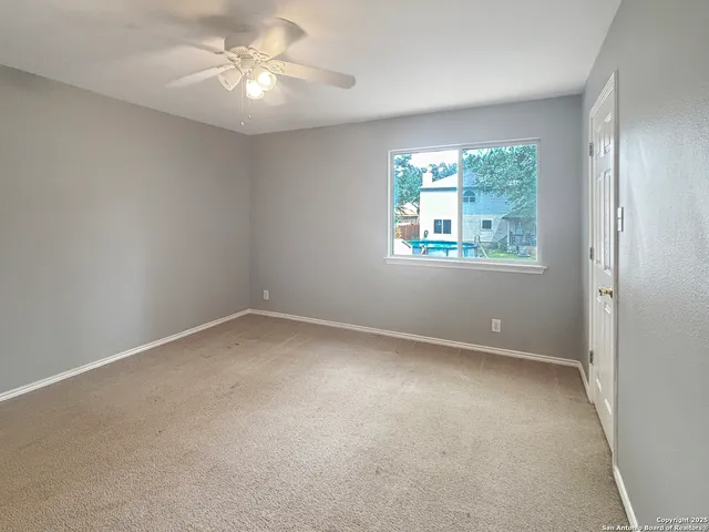 an empty room with a window and a fan