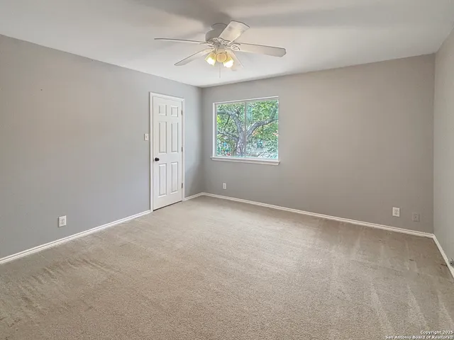 en empty room with windows and ceiling fan