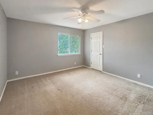 an empty room with windows and fan