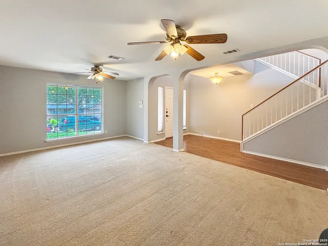 an empty room with windows and ceiling fan