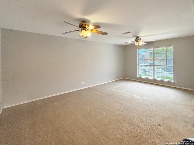 an empty room with windows and fan