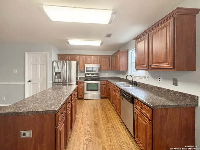 a kitchen with stainless steel appliances granite countertop a stove a sink dishwasher and a refrigerator with wooden cabinets