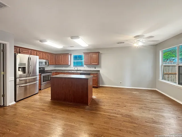 a kitchen with stainless steel appliances granite countertop a stove top oven a sink and a refrigerator