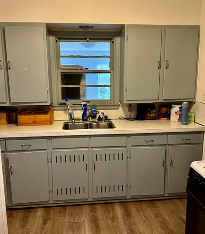 a kitchen with granite countertop white cabinets sink and a stove