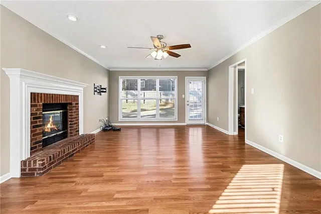 an empty room with wooden floor fireplace and windows